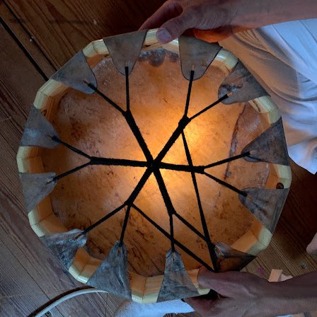 Un tambor chamánico templándose bajo la luz de una vela 